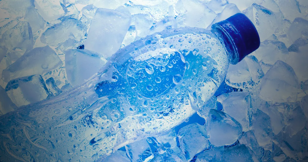 A plastic bottle rests atop a bed of ice, showcasing its cool surroundings in a refreshing setting.