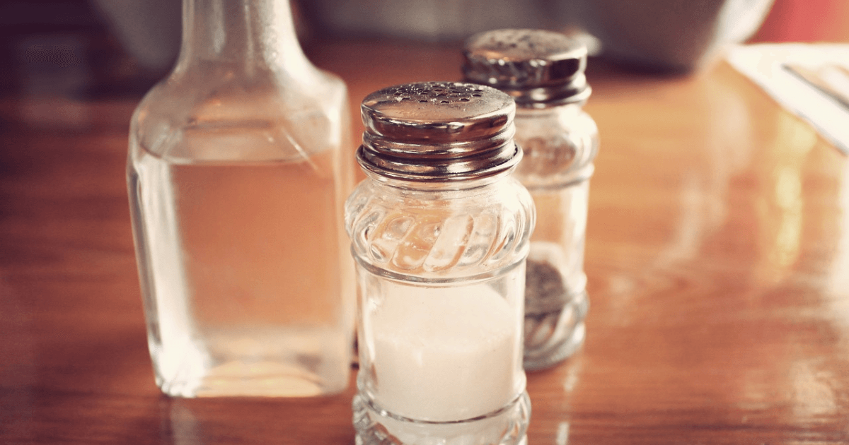 Salt and vinegar placed on a dining table, ready to clean the copper water bottle.