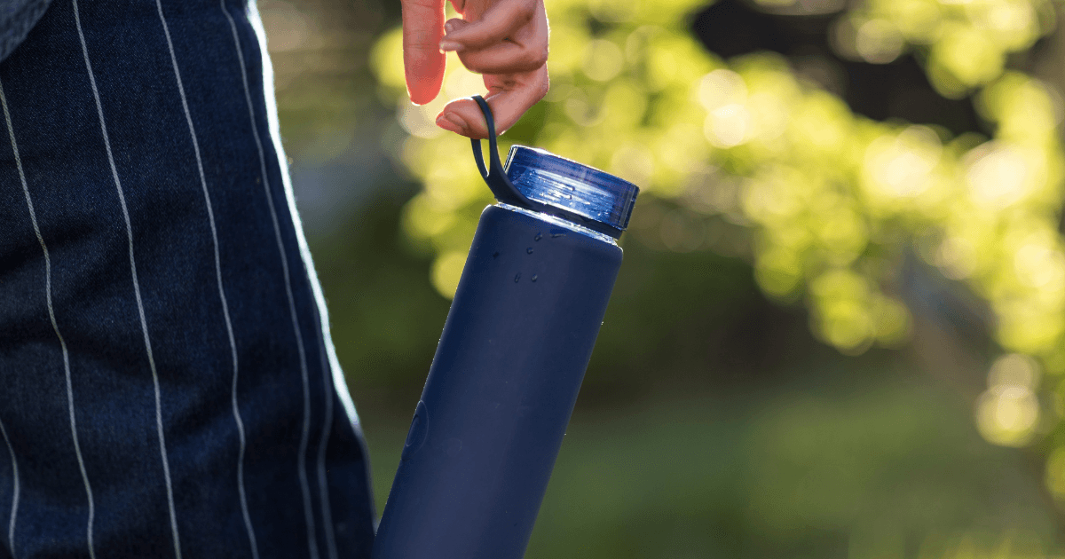 A person grasping a blue water bottle, showcasing hydration and outdoor activity.