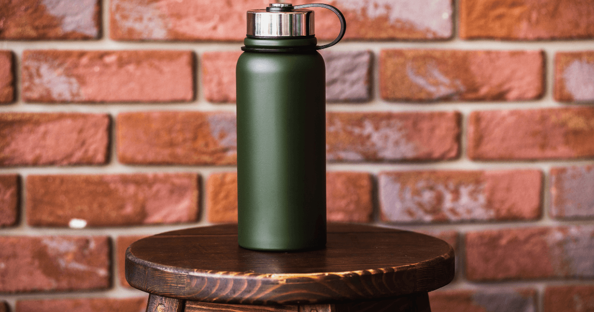 A green water bottle placed on a wooden stool, showcasing a simple and natural aesthetic.