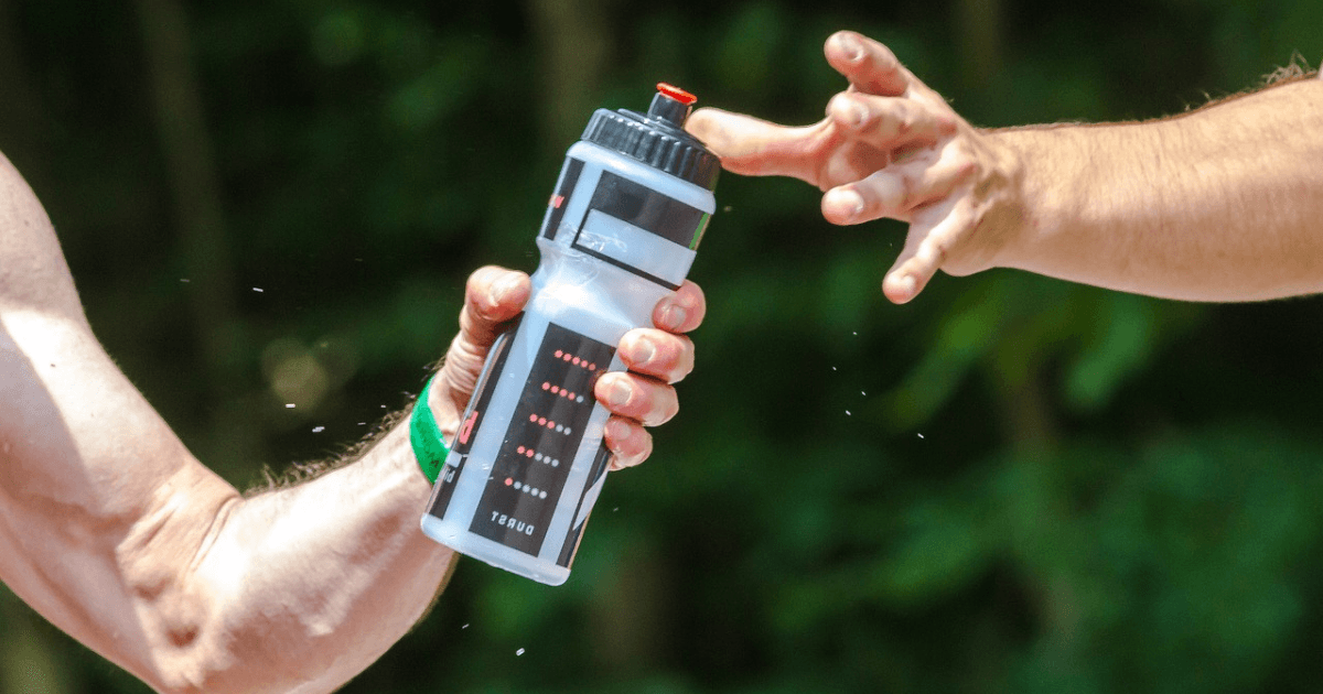 Two men are standing side by side, each holding a water bottle in their hands.