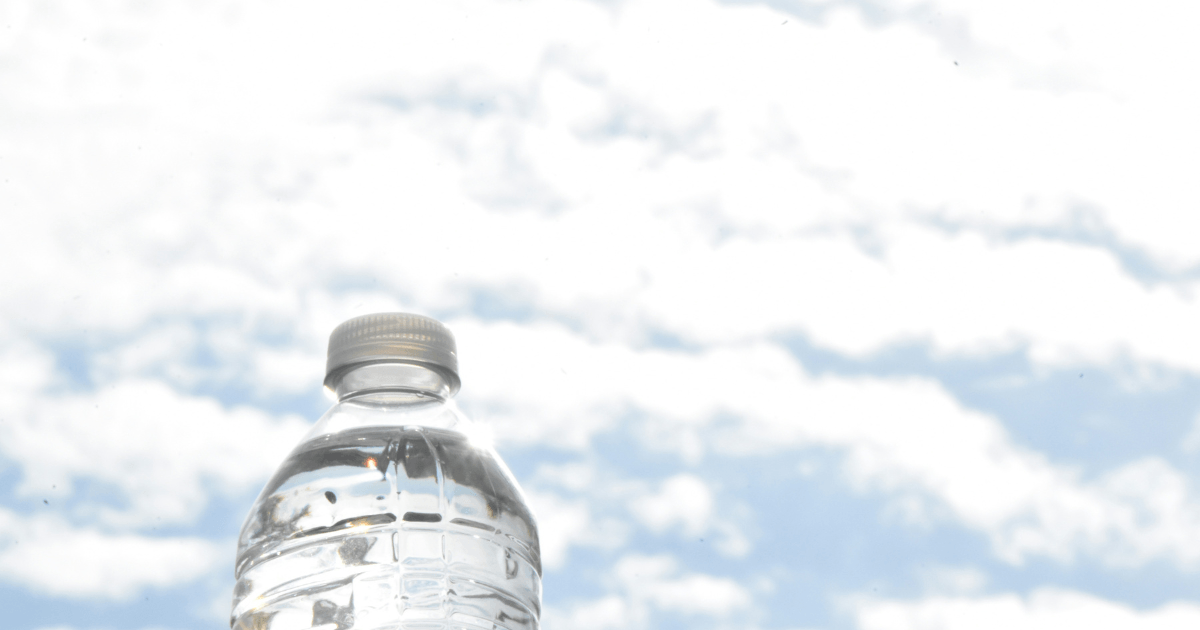 A clear bottle of water placed on a wooden table, reflecting light and showcasing its refreshing contents.
