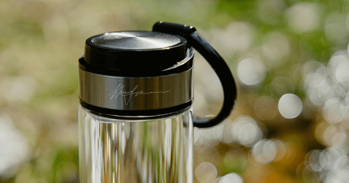 A clear glass water bottle featuring a sleek black lid, ideal for hydration on the go.