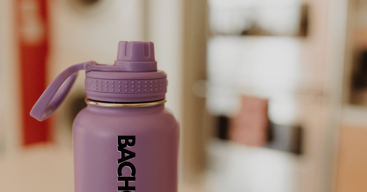 A purple water bottle featuring the word "bach" prominently displayed on its surface.