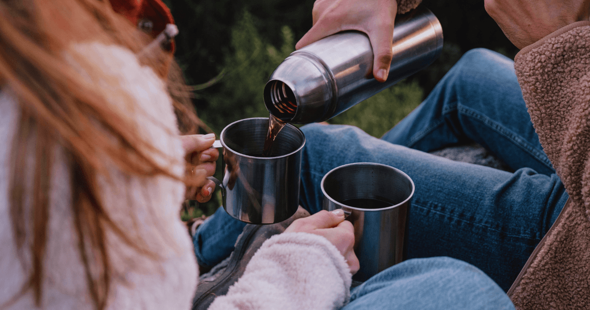 Two individuals on the ground, each with a cup of water, sharing a serene moment in a relaxed setting.