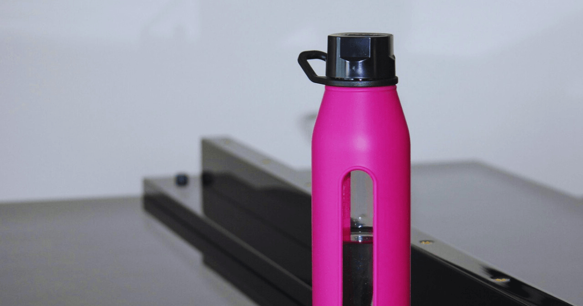 A pink water bottle placed on a table, showcasing its vibrant color against the neutral surface.