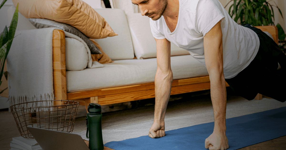 A man performing a push-up on a yoga mat, a water bottle is placed next to him.