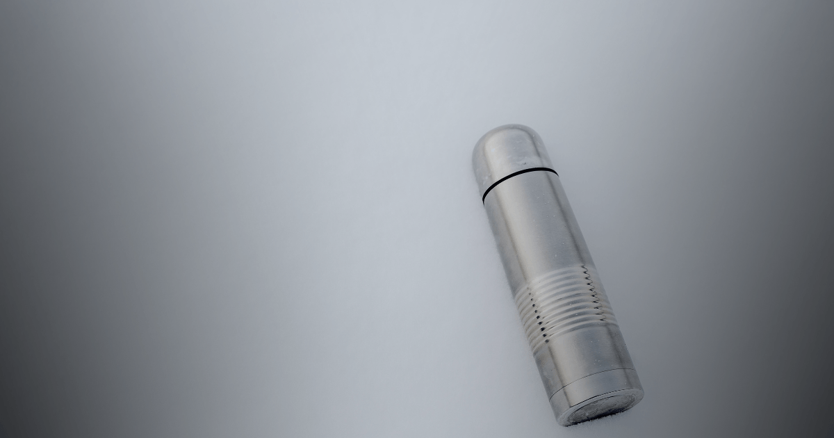 A silver lighter rests elegantly on a smooth gray surface, showcasing its sleek design and reflective finish.
