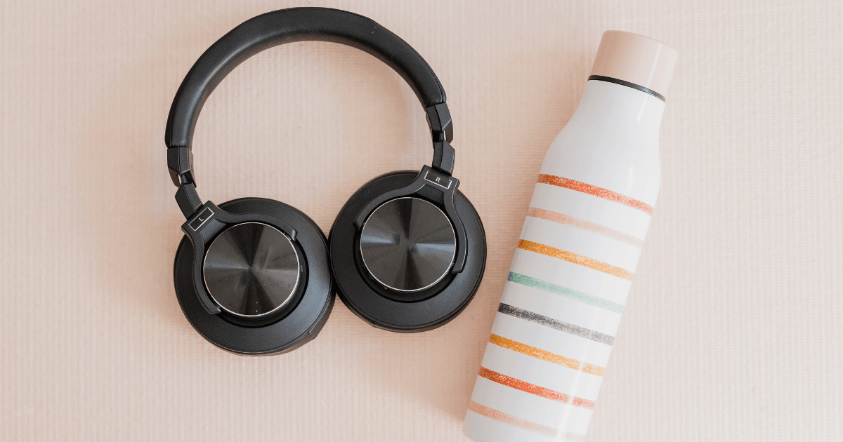 Headphones and a water bottle placed on a vibrant pink background, creating a stylish and refreshing aesthetic.