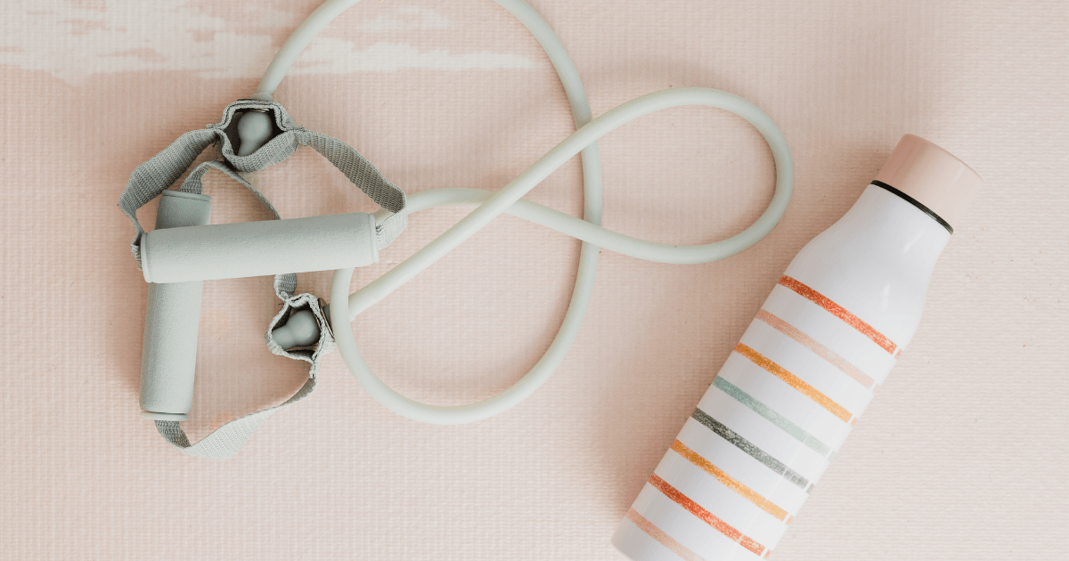 A water bottle, a rope, and a pair of leggings arranged on a flat surface, showcasing fitness and outdoor activity essentials.