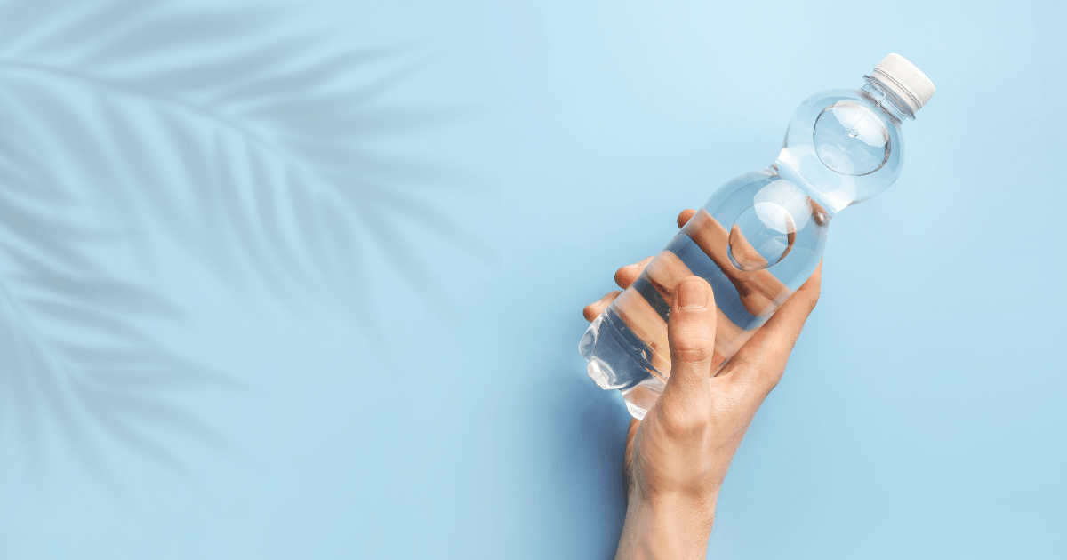 A hand grasping a clear plastic bottle filled with water, showcasing hydration and environmental awareness.