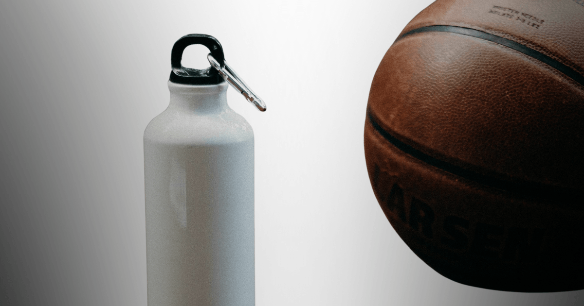 A basketball rests beside a water bottle, symbolizing hydration and sportsmanship in an athletic setting.