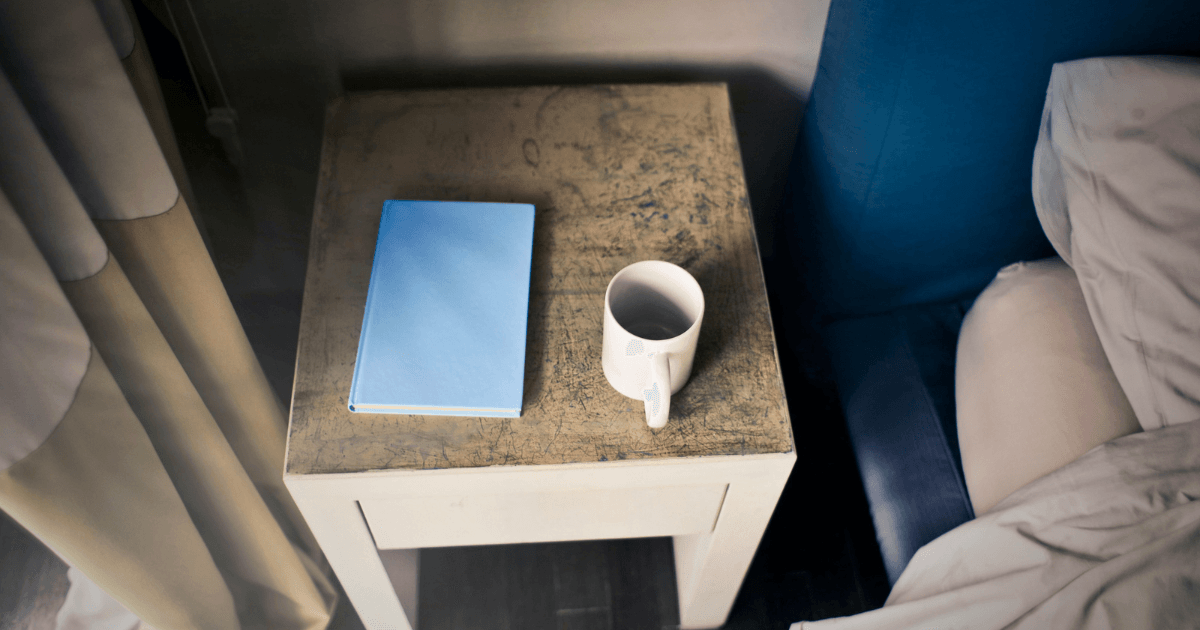 A coffee cup sits beside an open book on a wooden table, creating a cozy reading atmosphere.