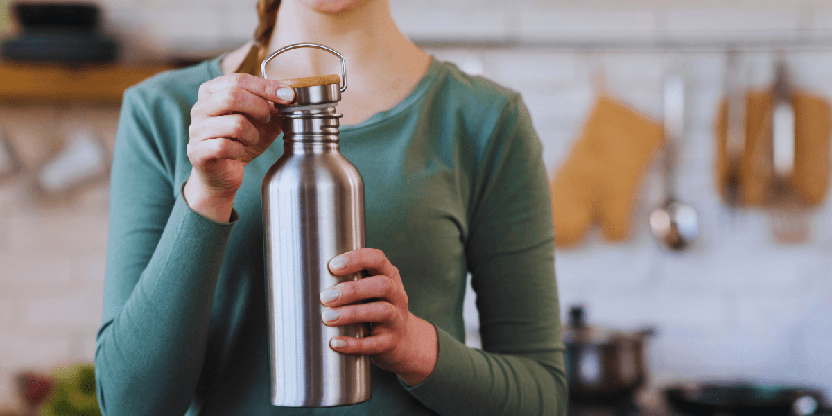 A woman holding a stainless steel water bottle in her hand.