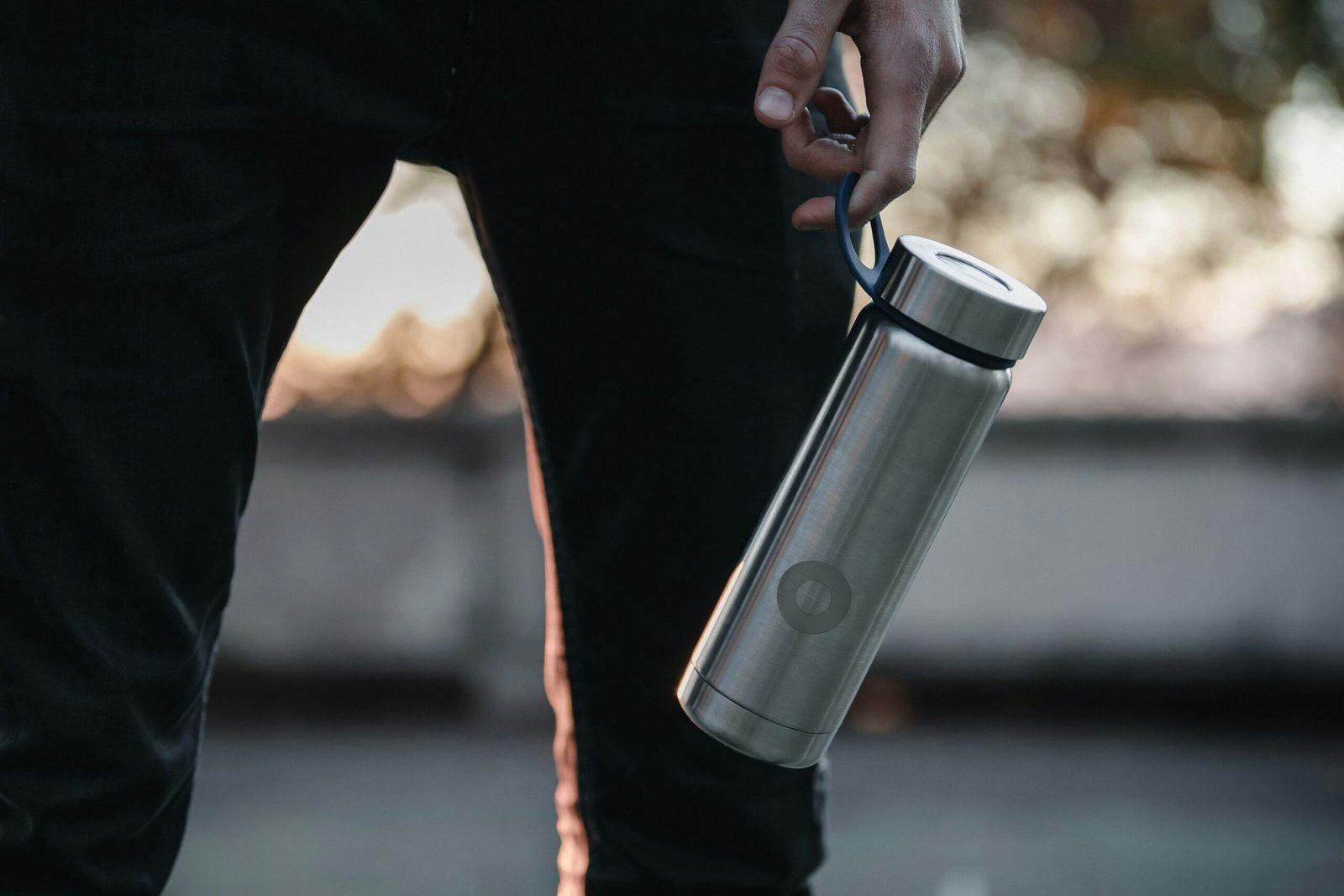 A person grasping a stainless steel water bottle, showcasing its sleek design and practical use for hydration.