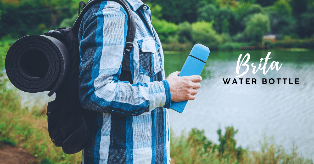 A man stands outdoors, holding a water bottle in one hand and a backpack slung over his shoulder.