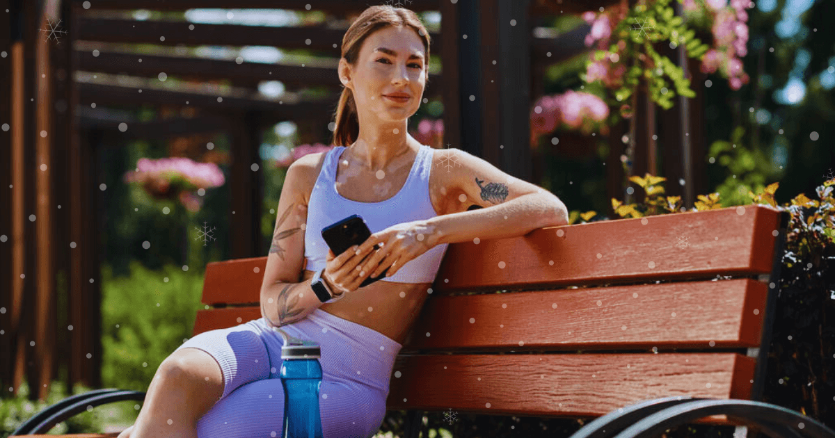 A woman seated on a bench, holding a water bottle, enjoying a moment of relaxation outdoors.