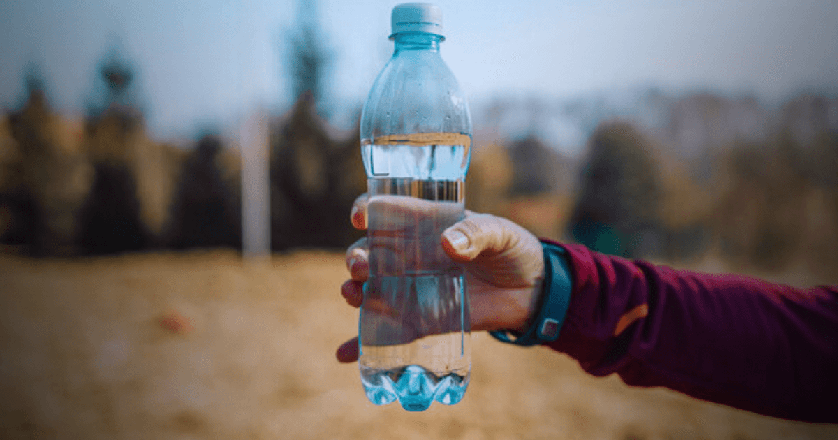 A person holding a clear bottle of water in their hand, ready to take a refreshing drink.
