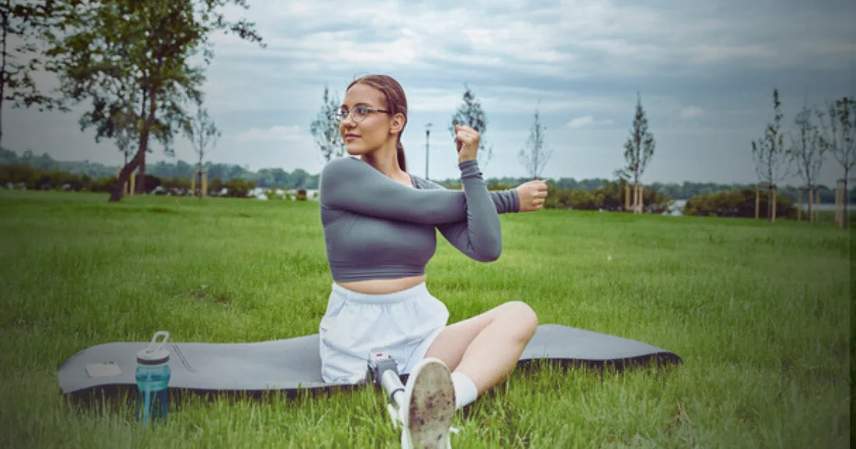 A woman relaxes on a mat in a grassy area with a water bottle, embracing the tranquility of nature.