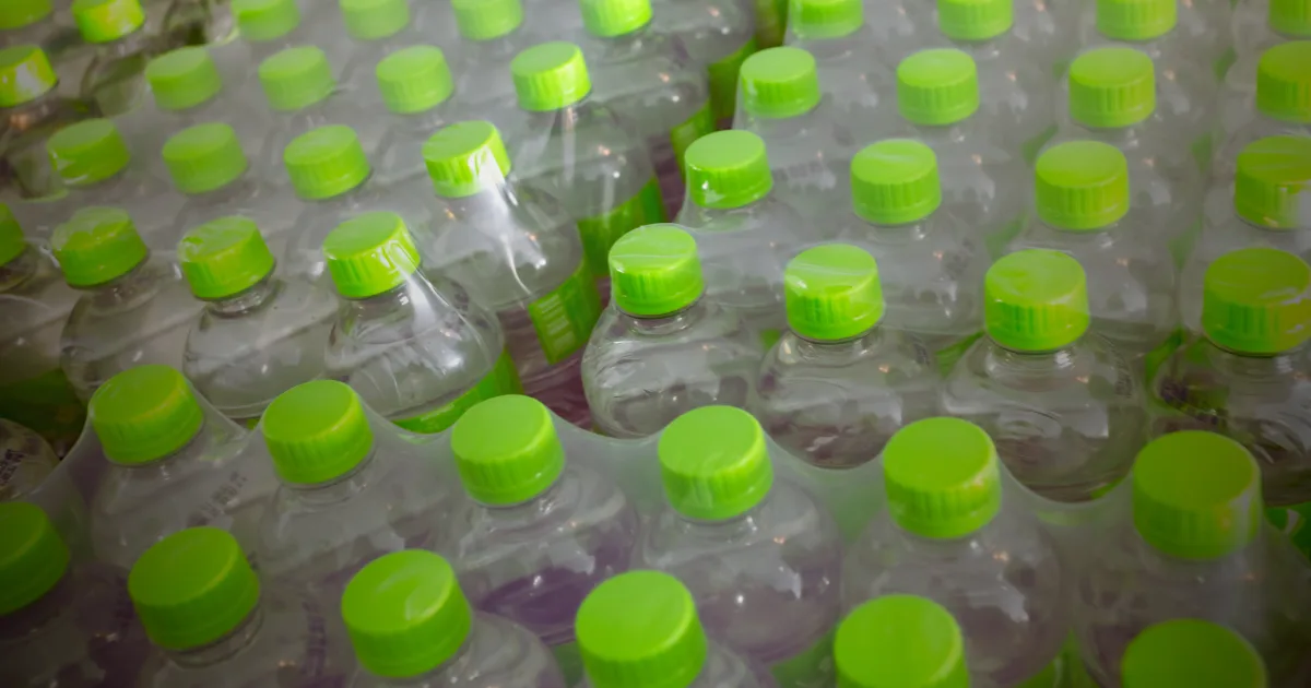 A row of plastic water bottles featuring green caps, arranged neatly in a straight line.
