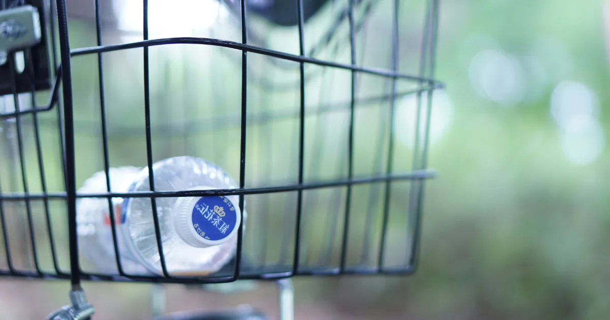 A bottle of water rests in a basket attached to a bicycle, ready for a refreshing ride.