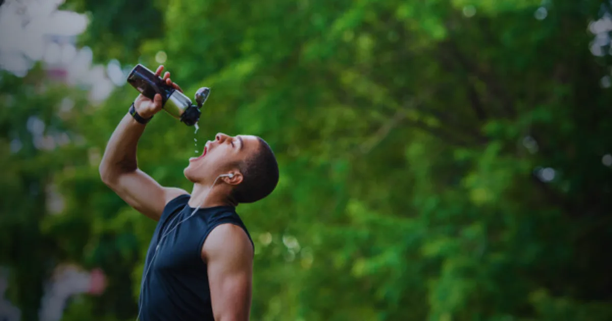 A man drinks from an Owala water bottle, refreshing himself with a sip of water.